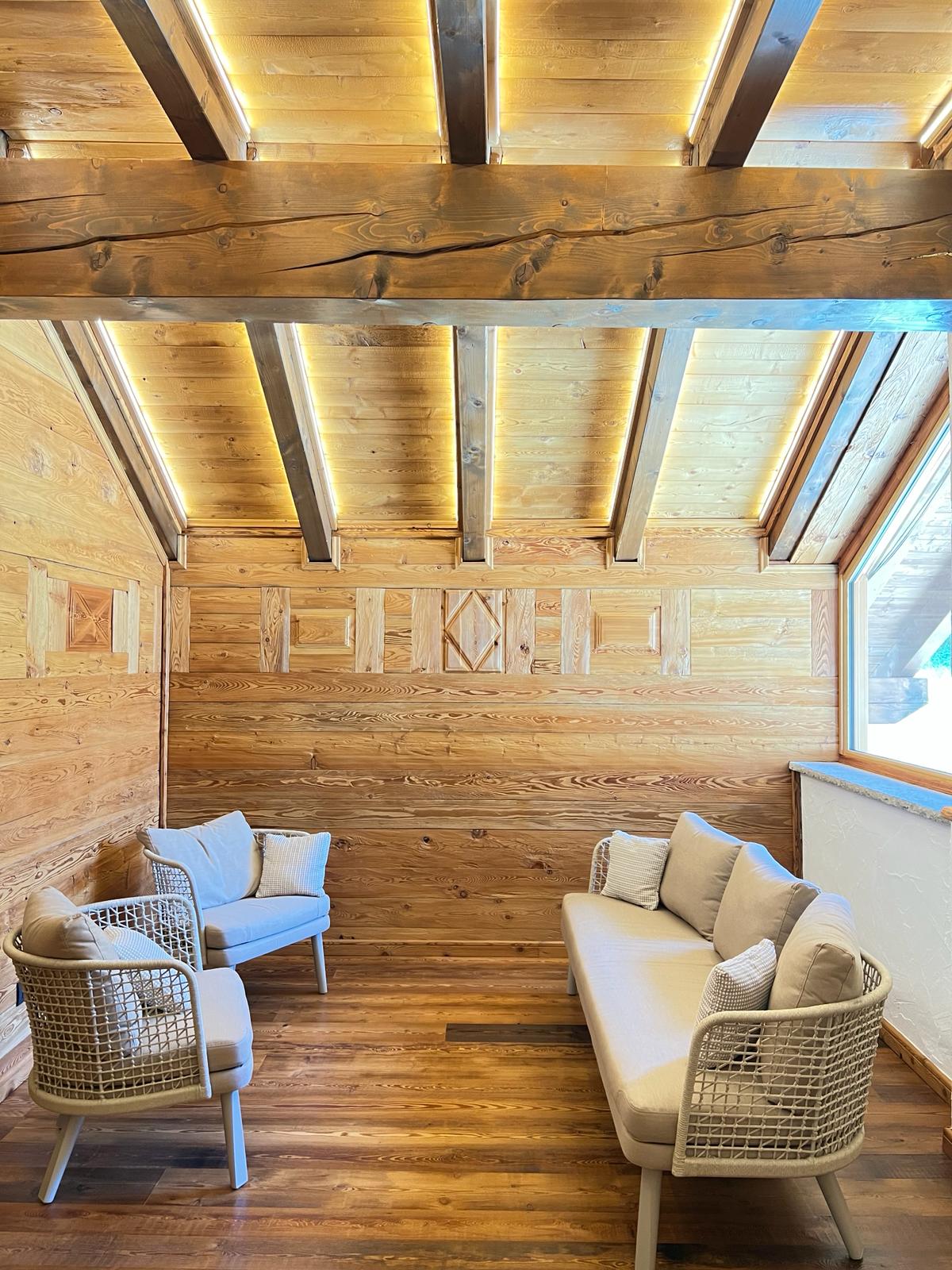 Ambiente rivestito in legno con travi a vista e pannelli decorativi